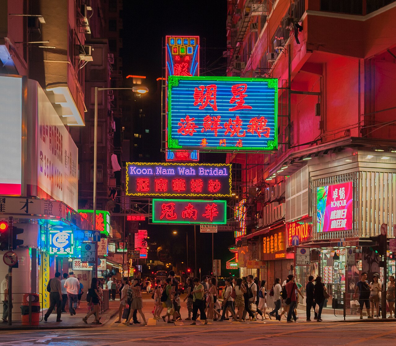 Signboards stacked above the pavement after dark.